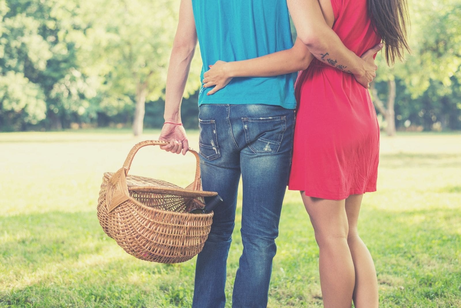 pareja desconocida llegando al parque con una cesta de picnic