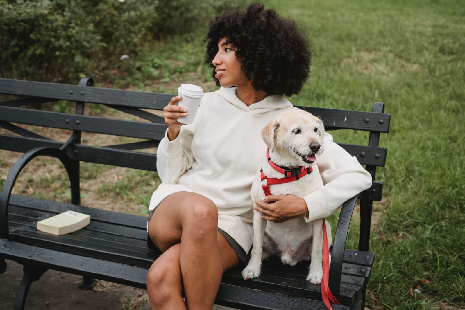 woman drinking coffee while sitting near dog
