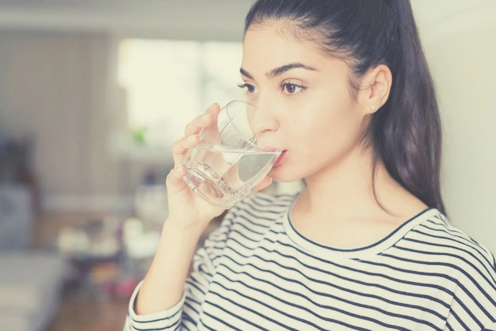 woman drinking water while thinking deeply 