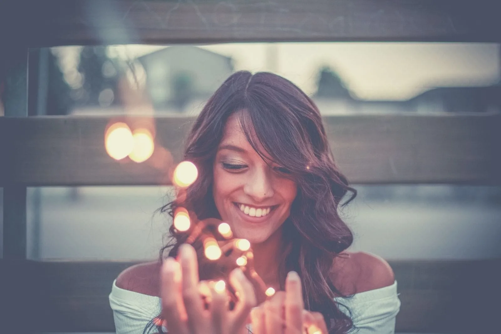 woman holding lights smiling and sitting outdoors