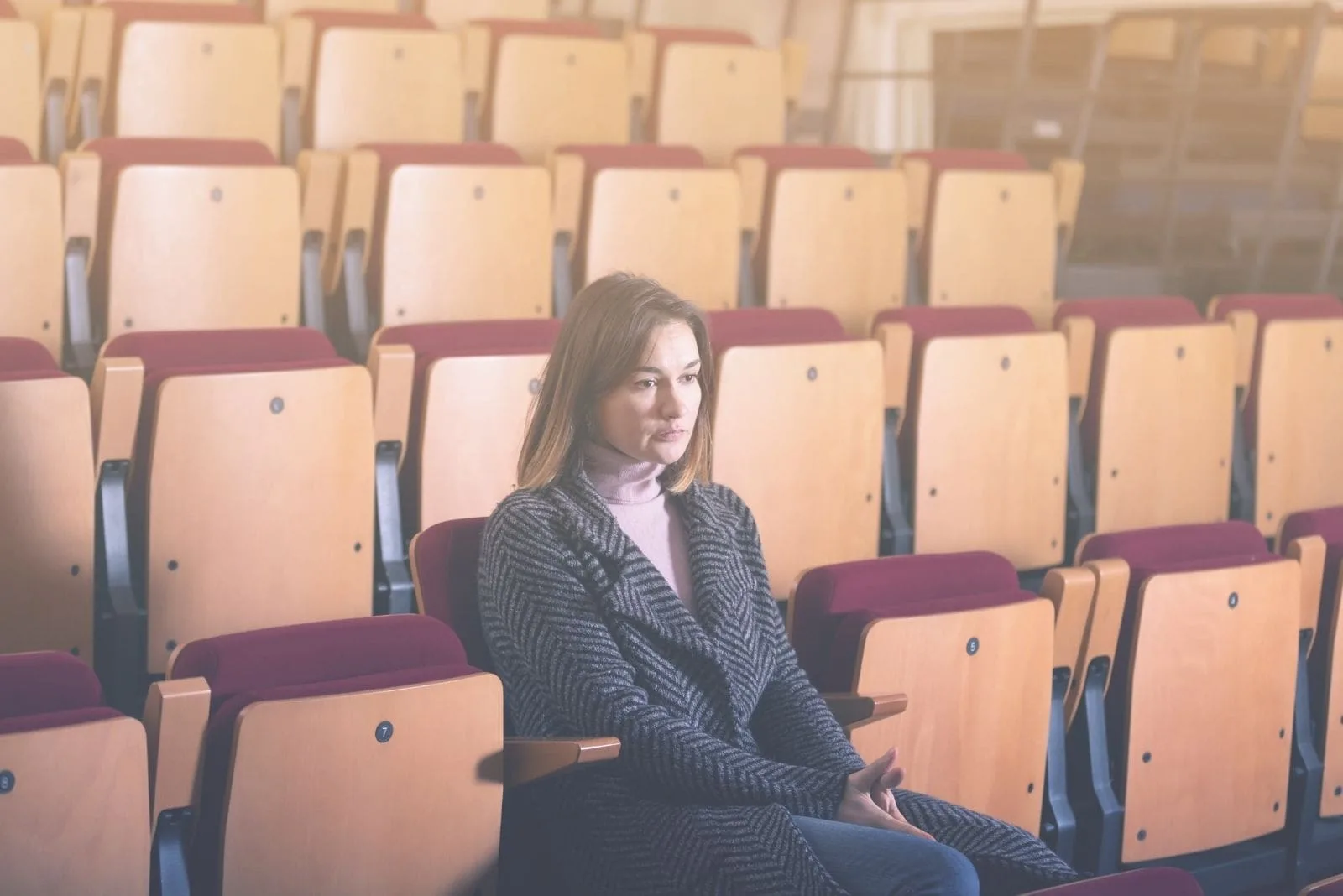 woman in the movie house alone waiting and pensive with empty seats