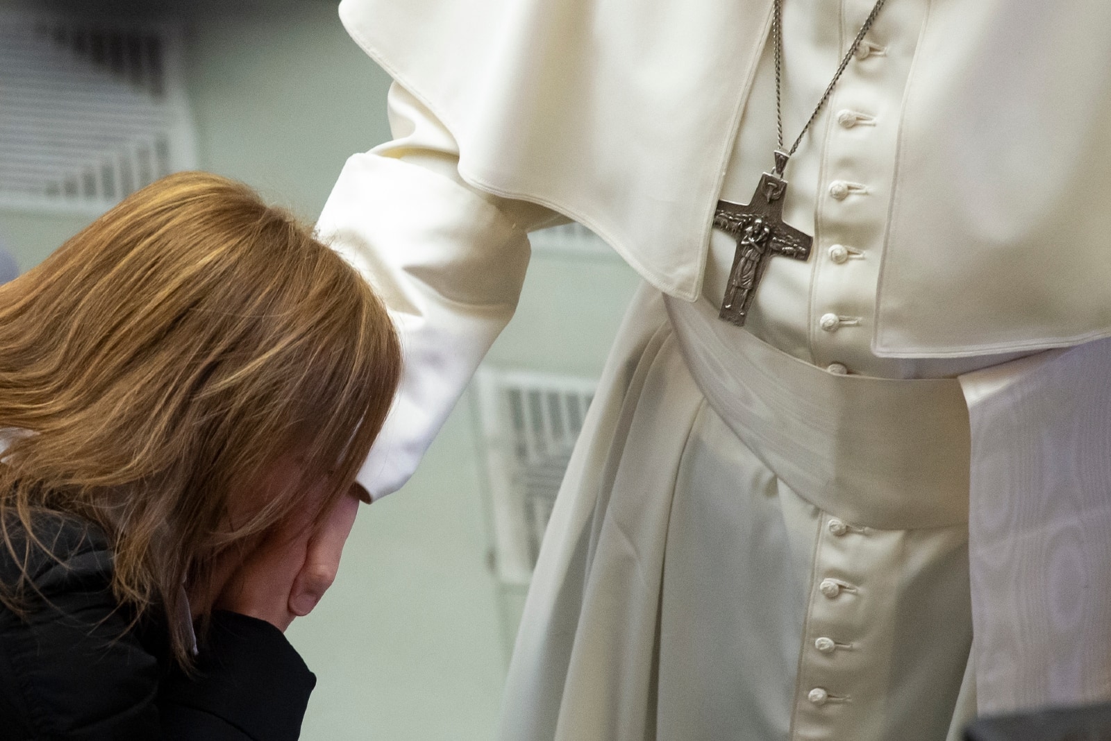 mujer con chaqueta negra besando la mano del papa en el vaticano