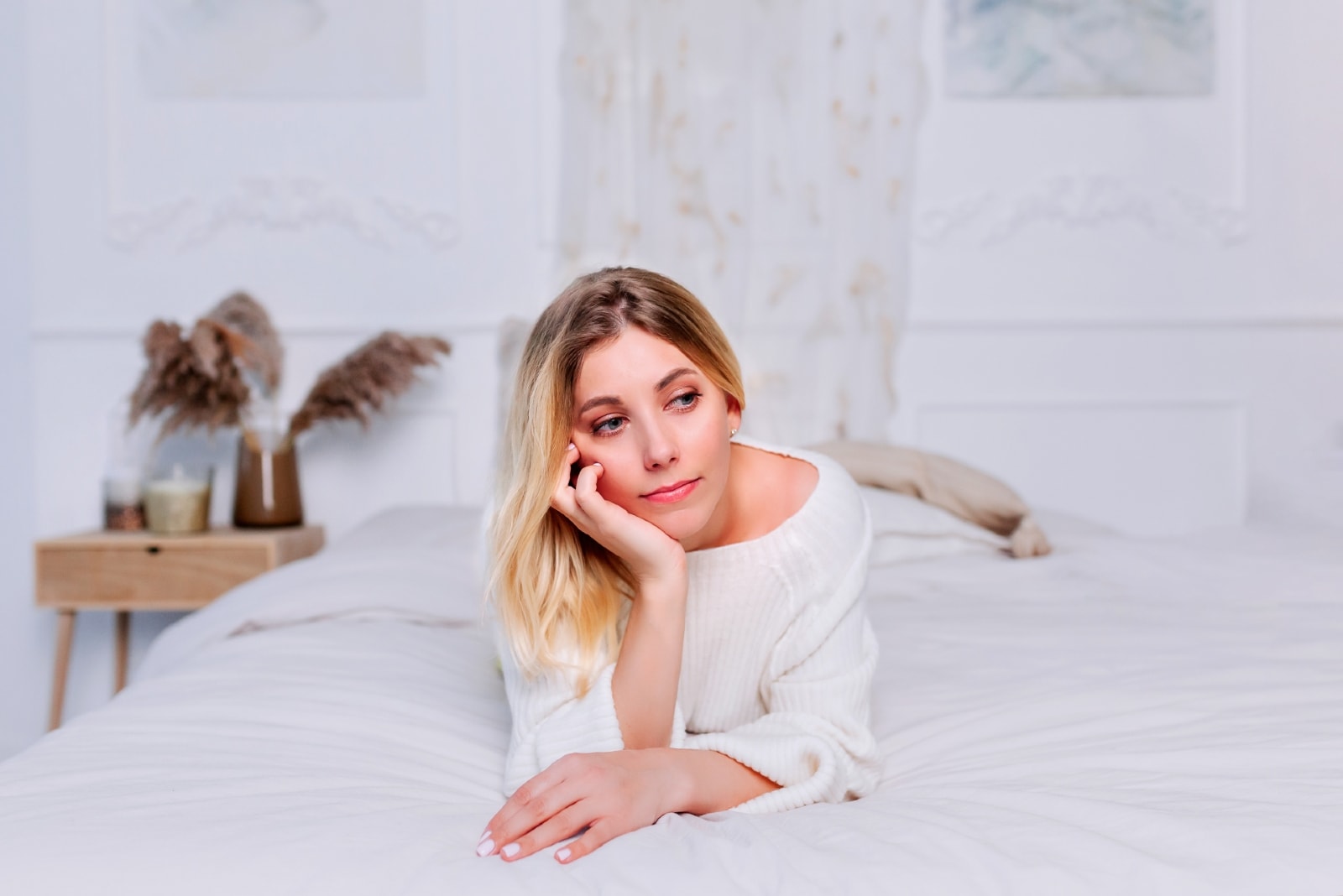 sad woman in white top laying on bed