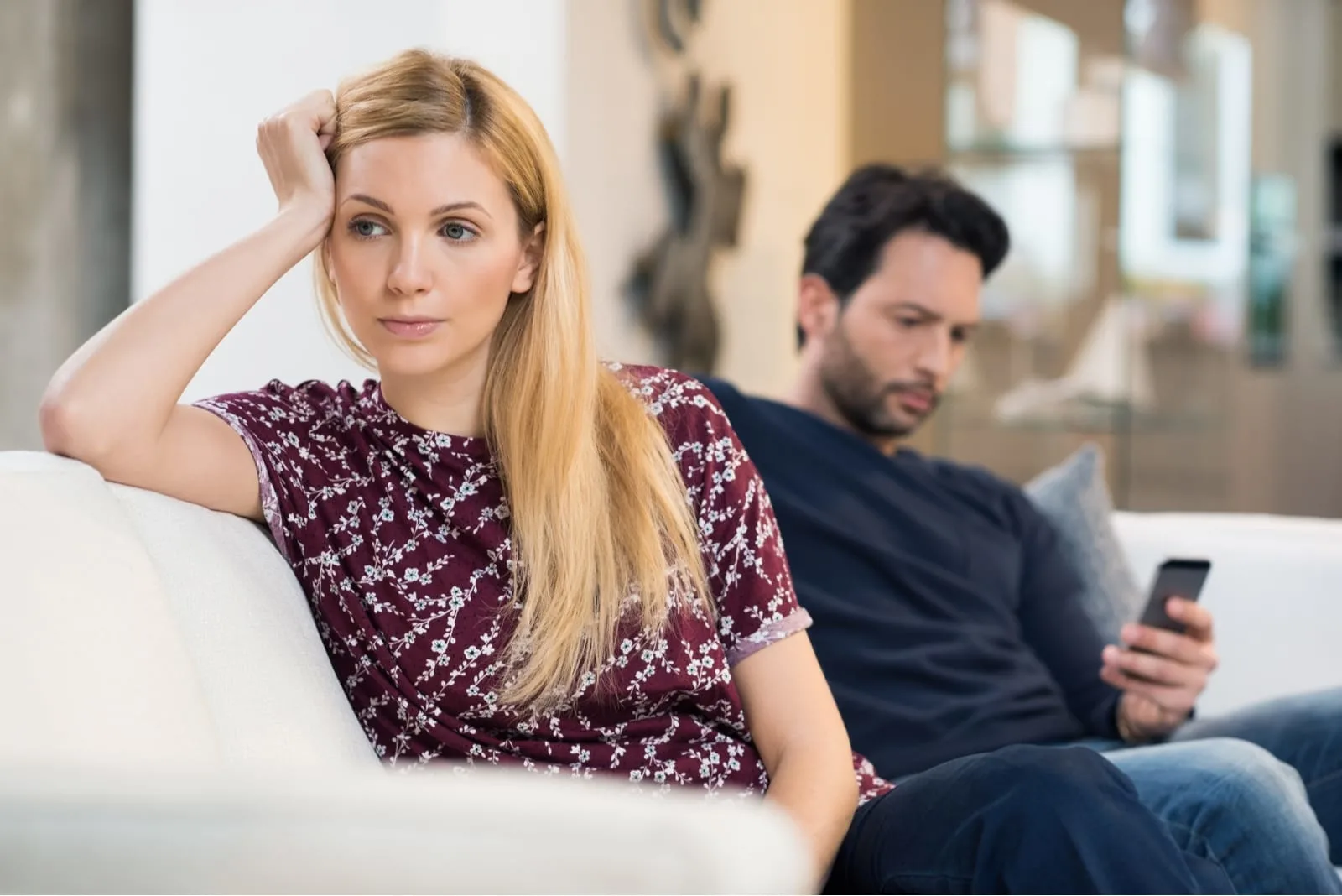 blonde woman leaning on sofa while sitting near man