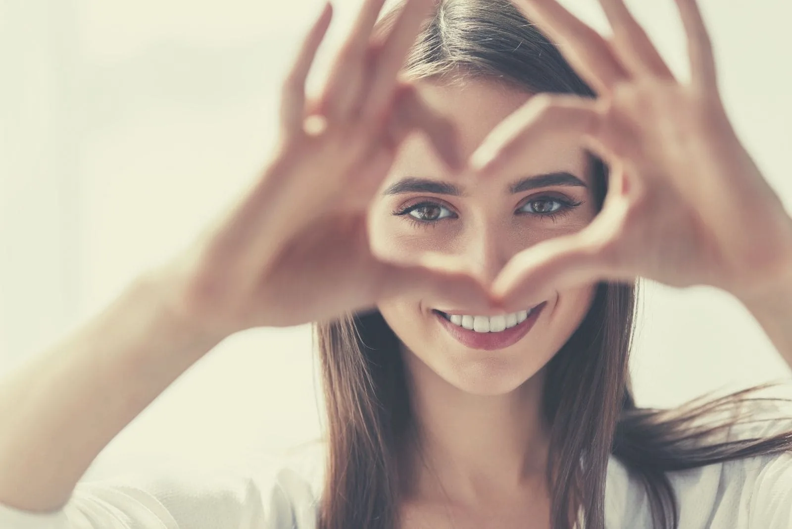 woman making hand sign of heart shaped focus on the face