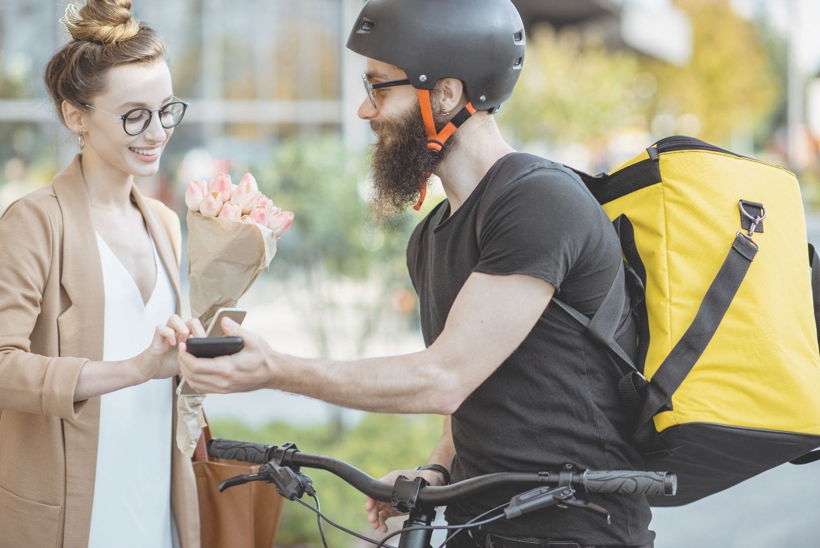 mujer recibiendo flores del repartidor en una bicicleta sosteniendo un gadget de recibo 