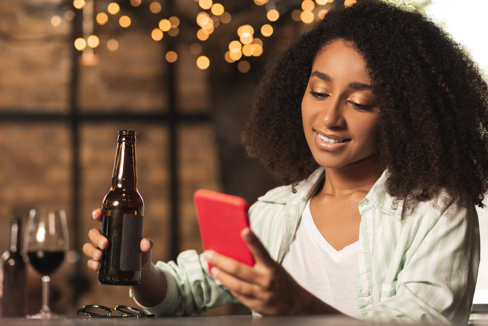 woman sitting drinking beer and key on phone