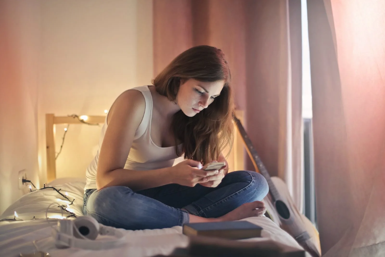 woman using smartphone while sitting on bed