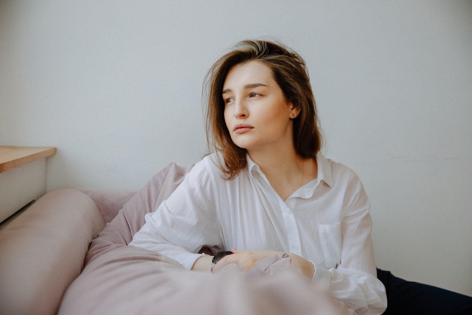 pensive woman in white shirt sitting on sofa