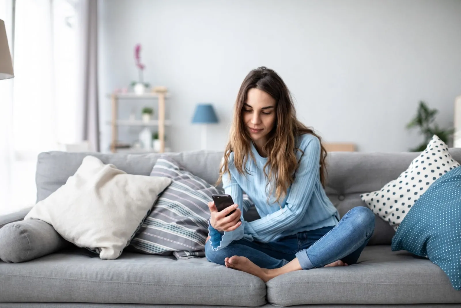woman sitting on sofa while looking at phone