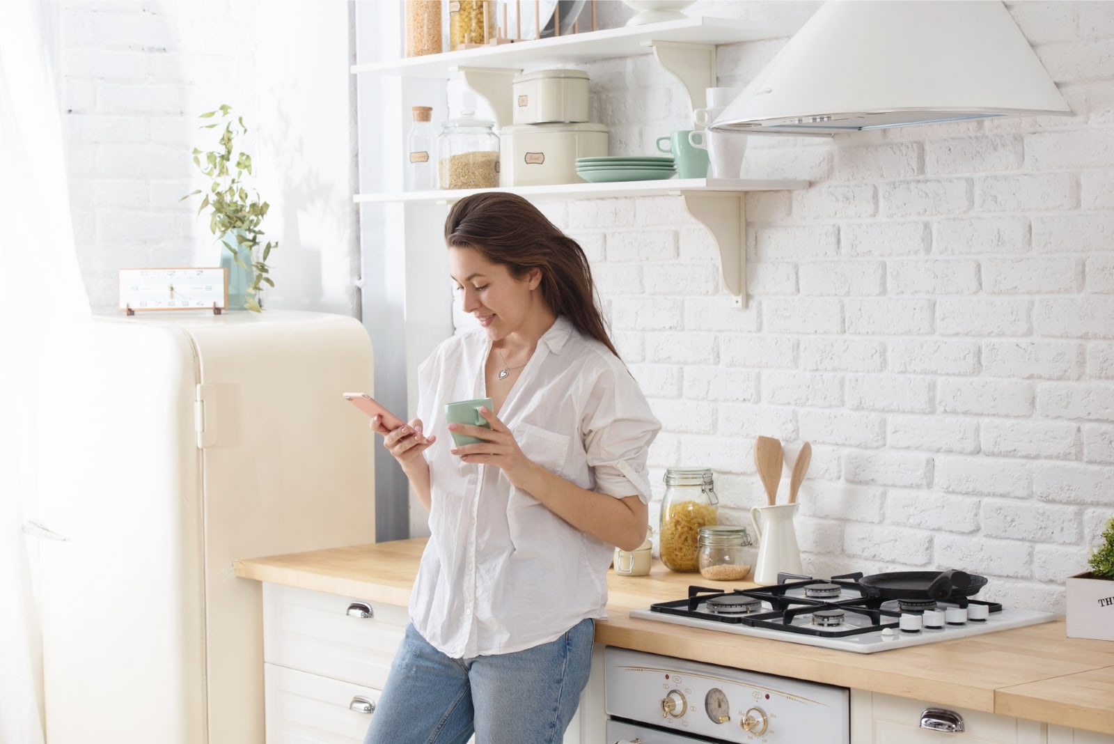 donna che usa lo smartphone in piedi in cucina