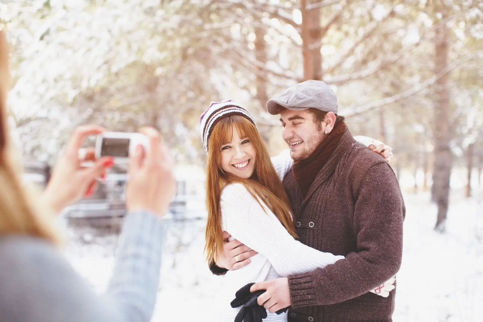 woman taking a picture of a sweet couple in the winter park