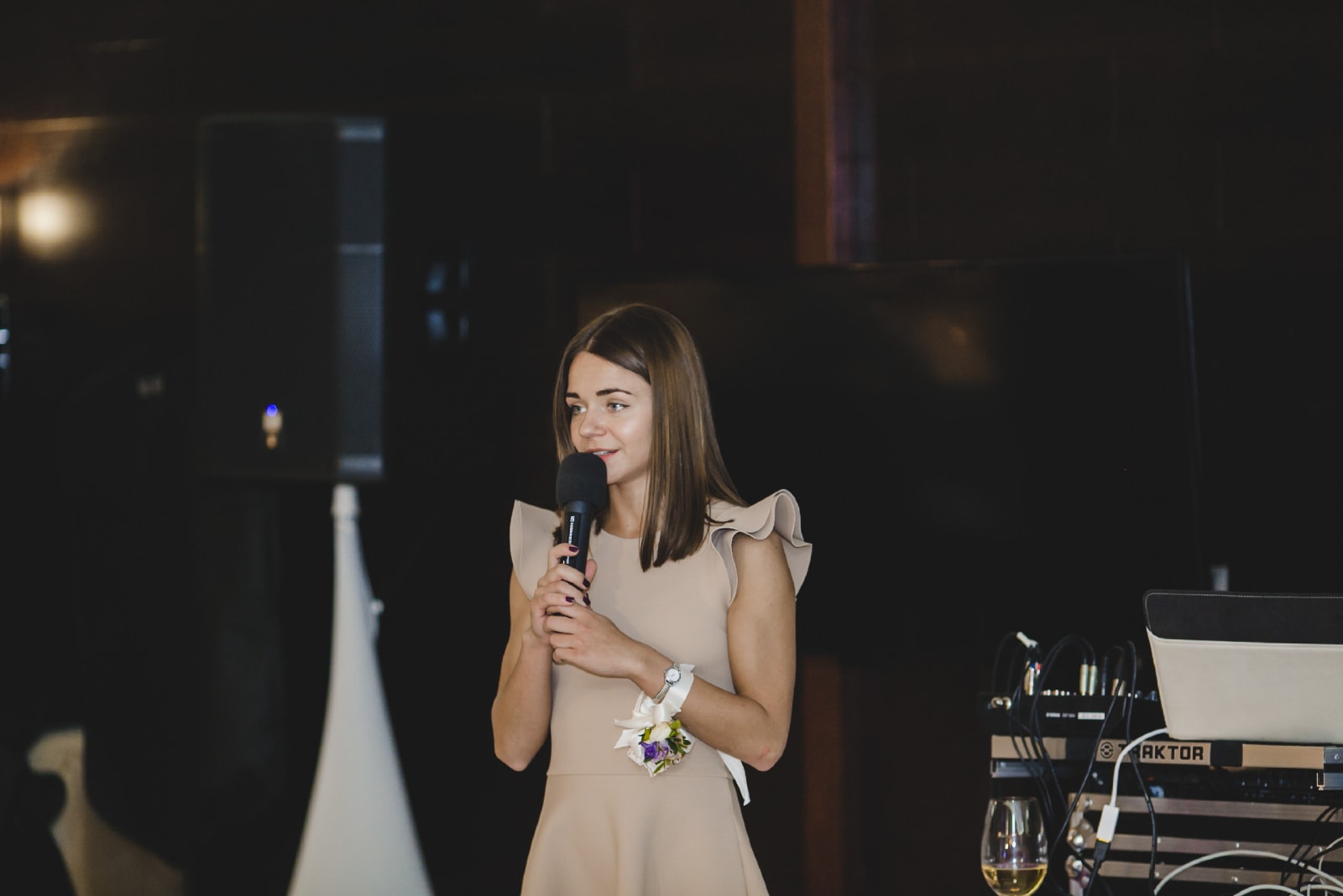 mujer con vestido beige hablando por microfono