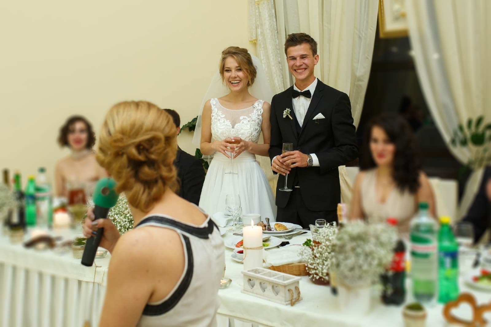 woman holding microphone while talking to groom and bride