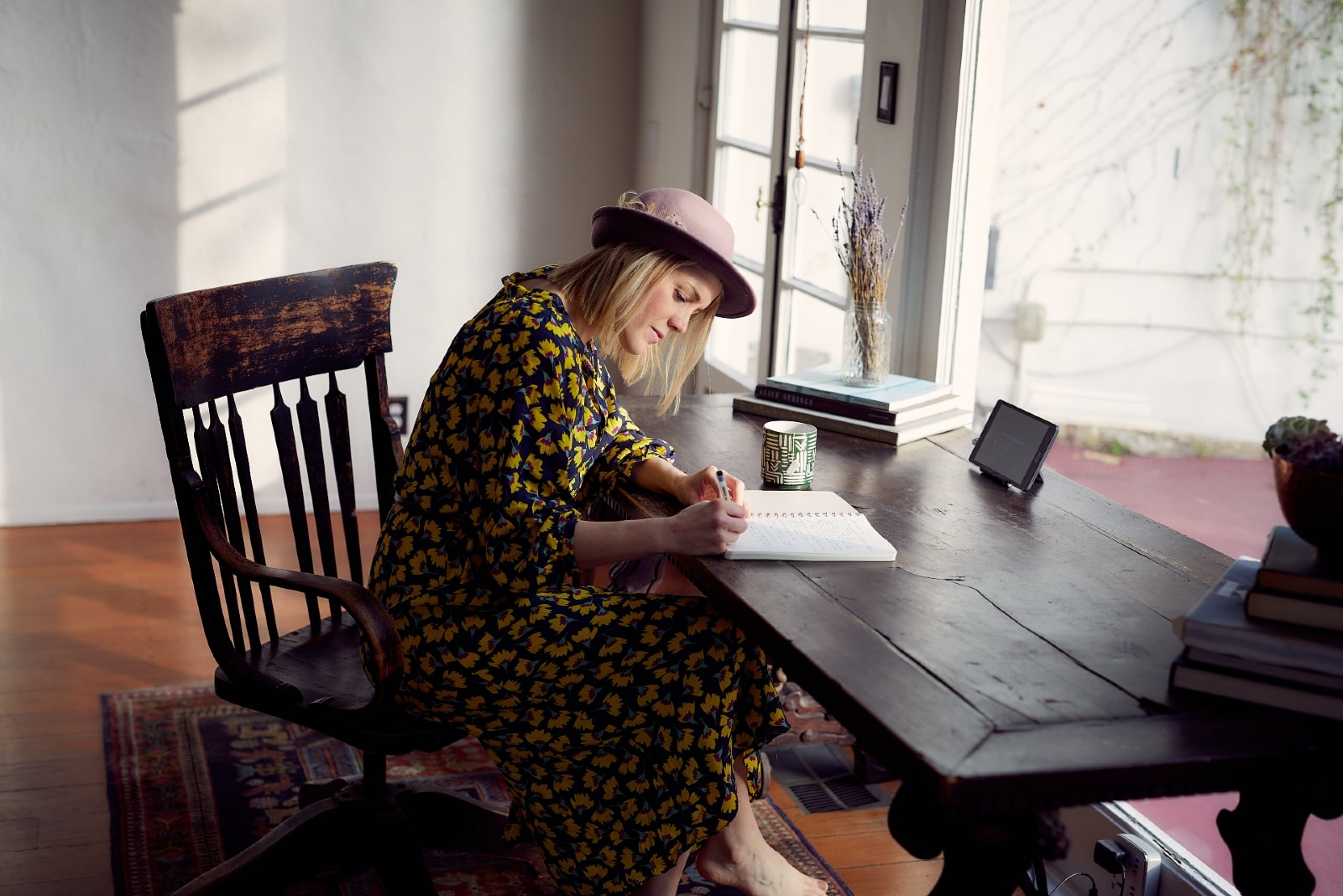 woman writing on notebook while sitting at table