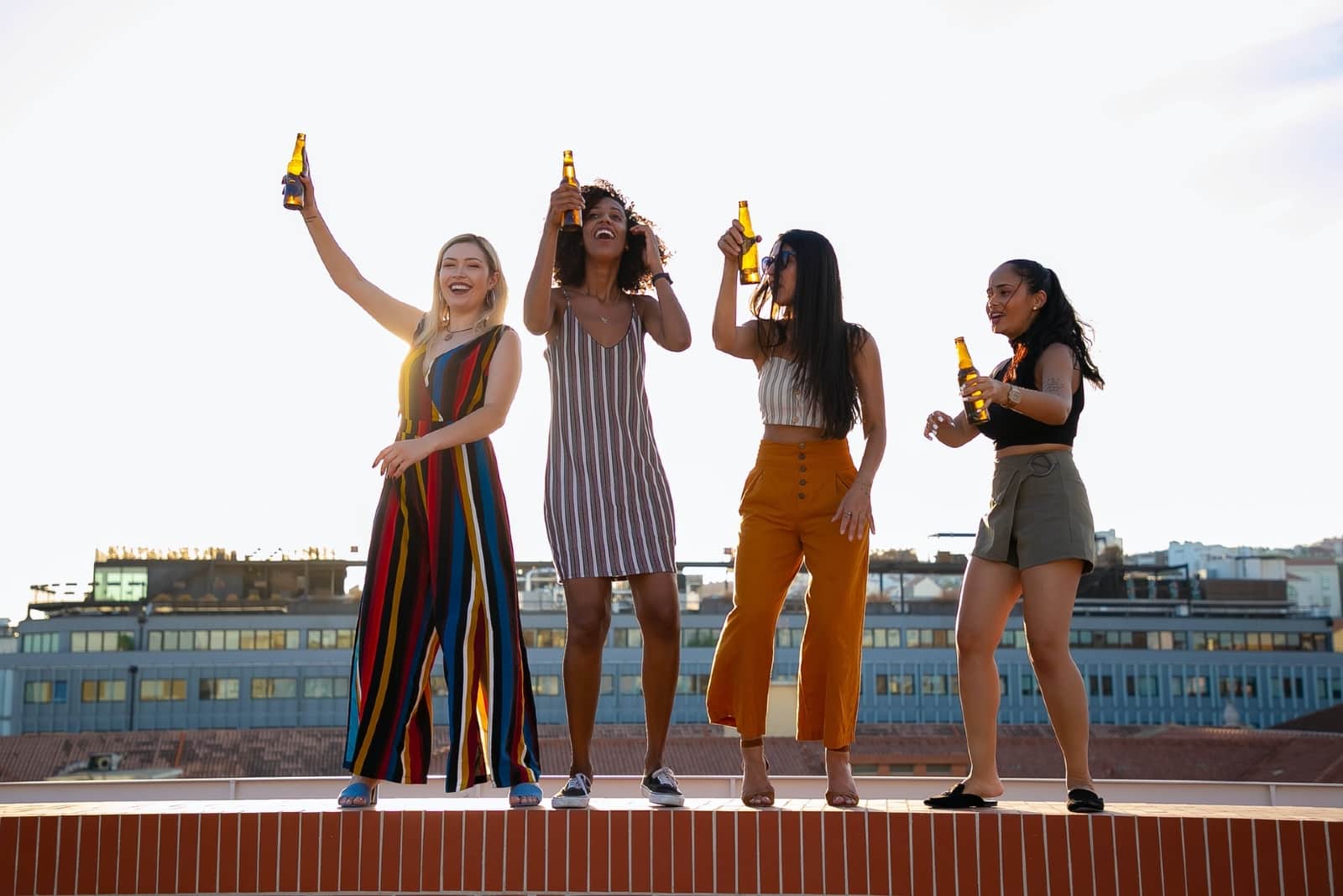 women dancing and drinking beer on rooftop