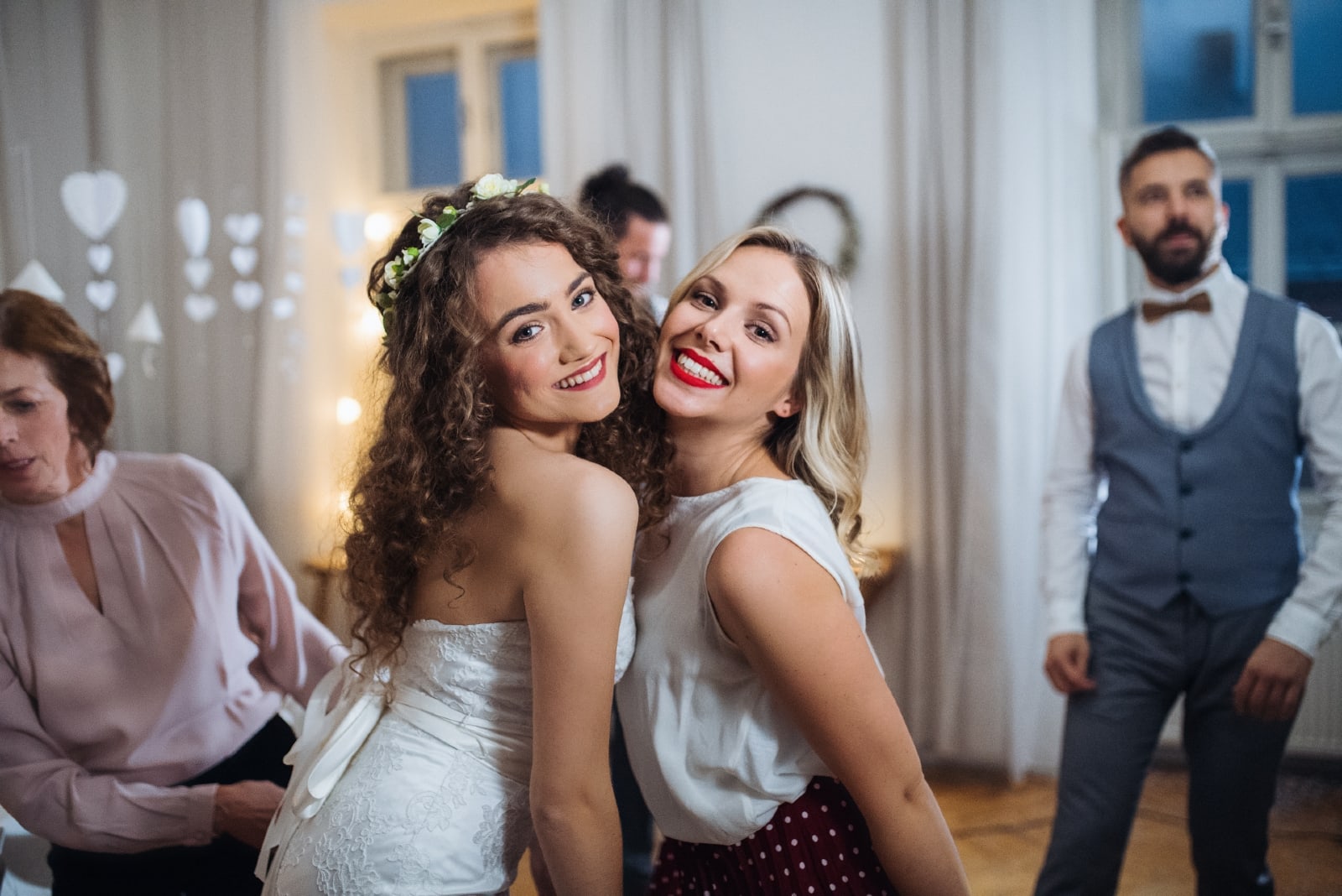 novia feliz y su hermana de pie en el interior