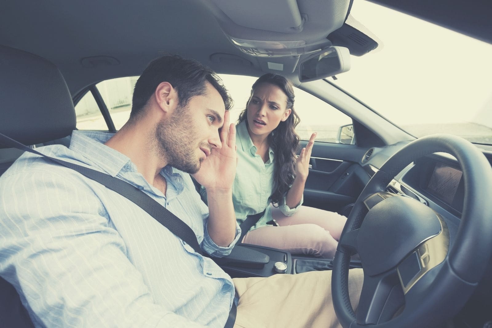 jovem casal a discutir dentro do carro, com o homem no banco do condutor a ficar irritado