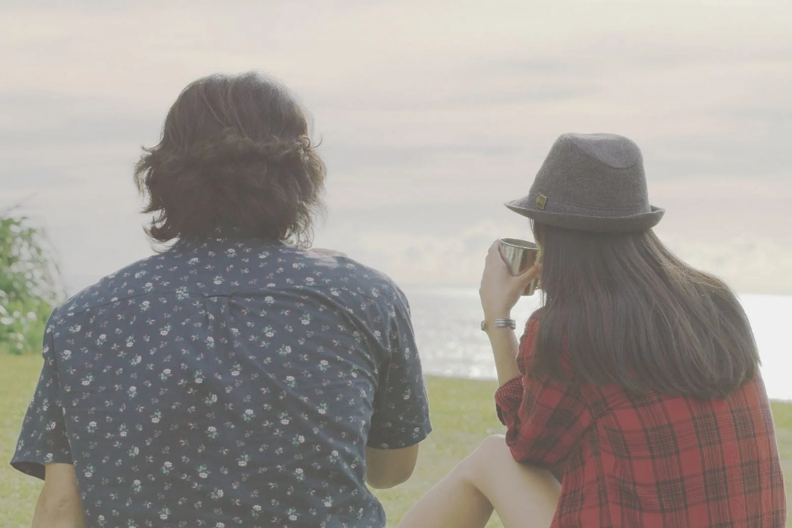 young couple talking outdoors drinking coffee near sitting near the body of water