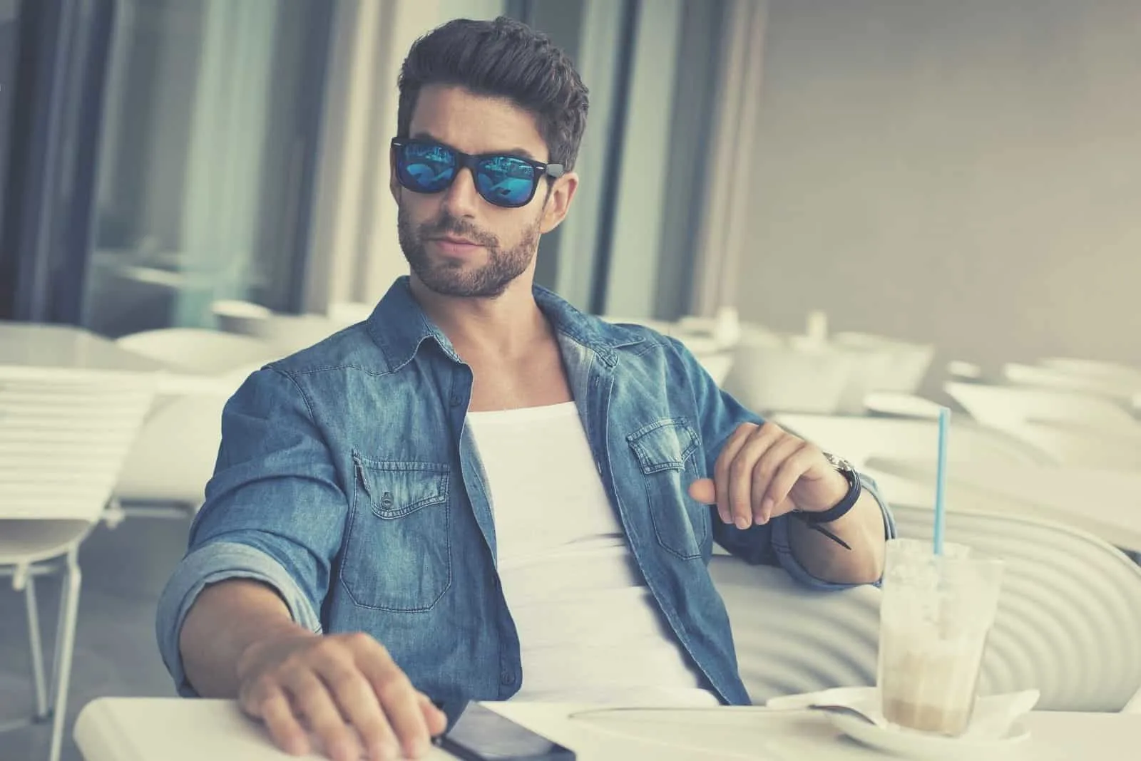 young handsome man sitting in the table wearing shades