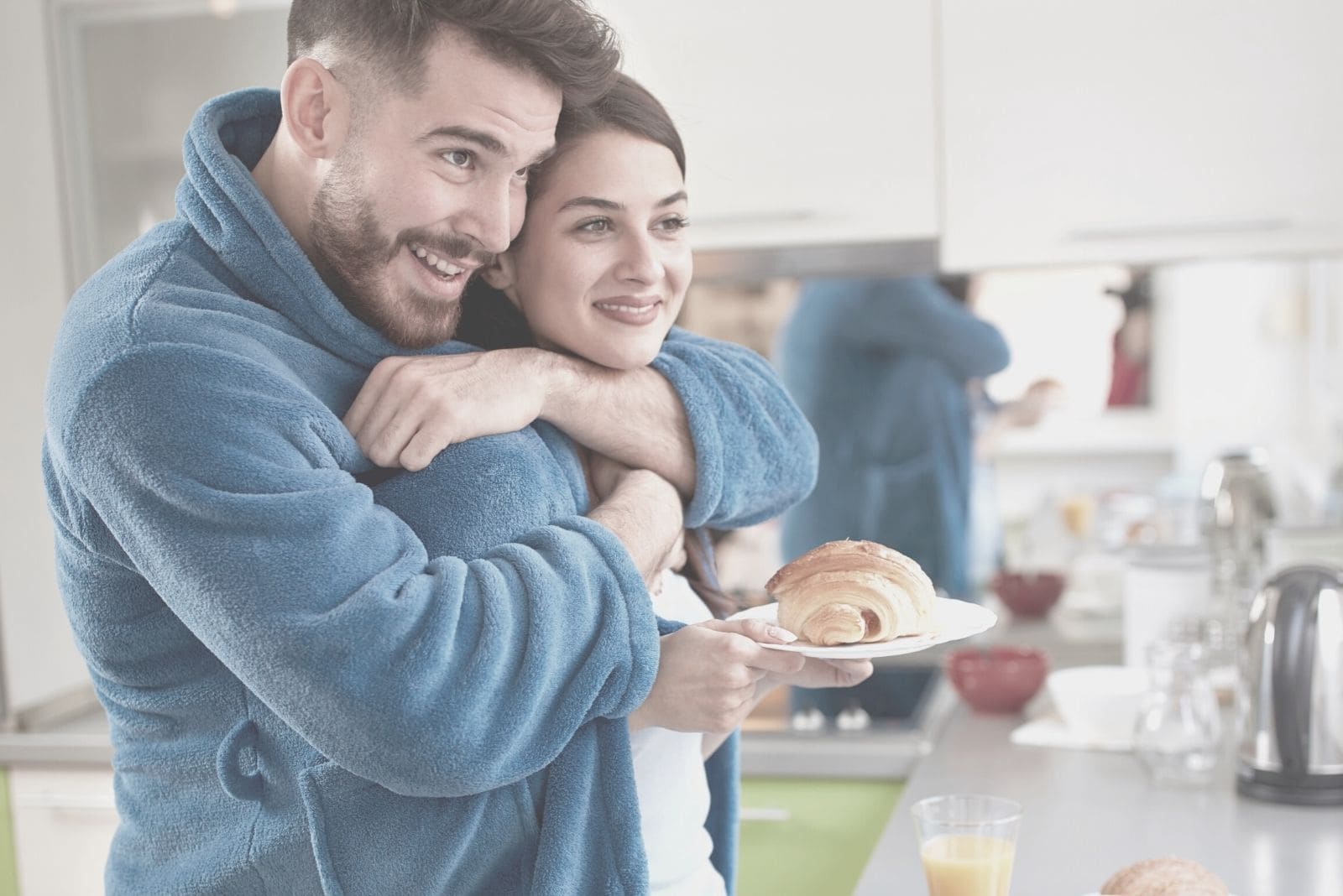 young man hugging wife in the kitchen bring baked bread 