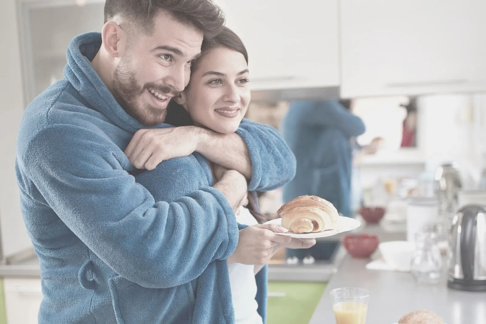 young man hugging wife in the kitchen bring baked bread 