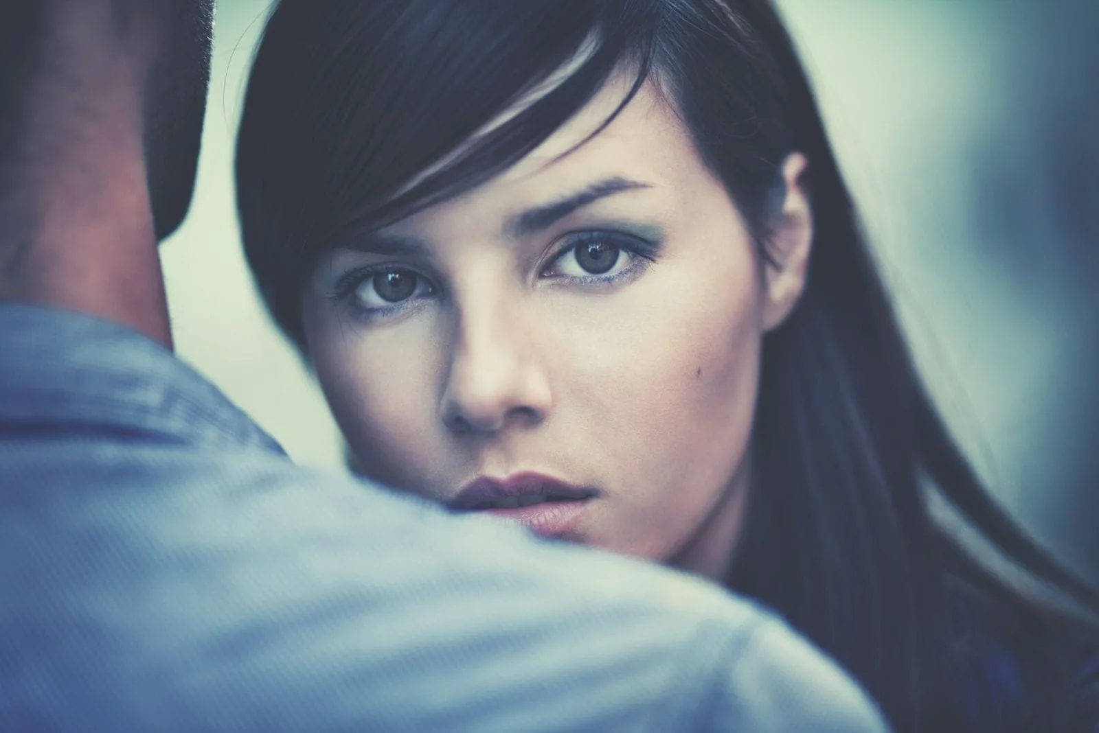 young pensive woman staring at the camera over a man's shoulder