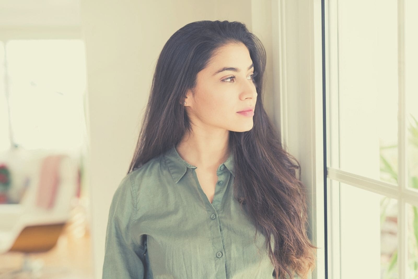 young woman leaning on the wall near the windows while looking outside