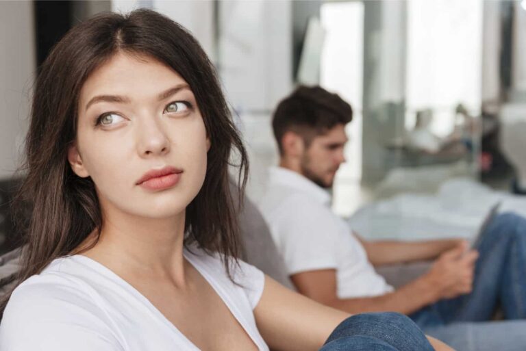 pensive woman in white t-shirt sitting near man