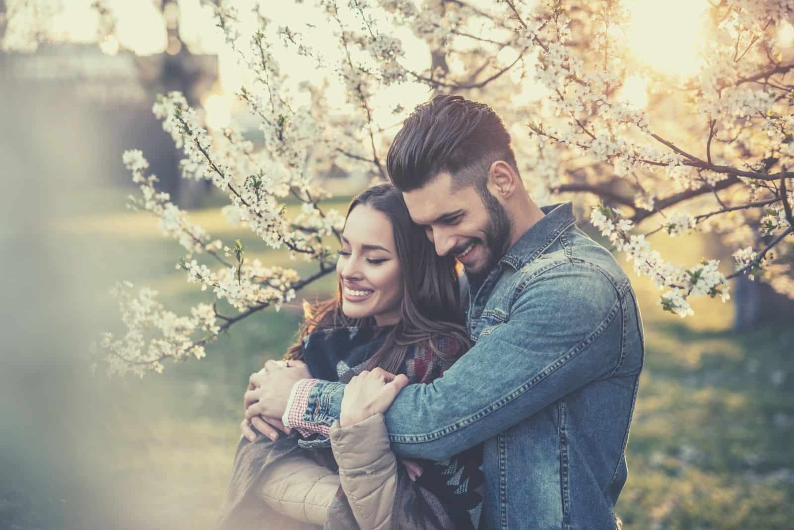 sweet couple hugging during autumn season near the flowered tree