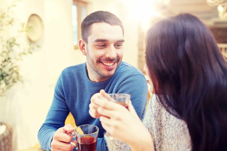 happy man and woman drinking tea while sitting in cafe