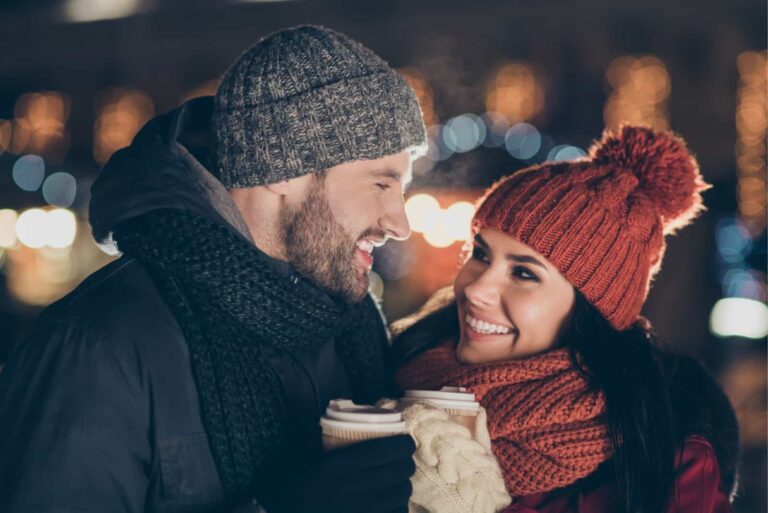 man and woman having coffee while standing on the street