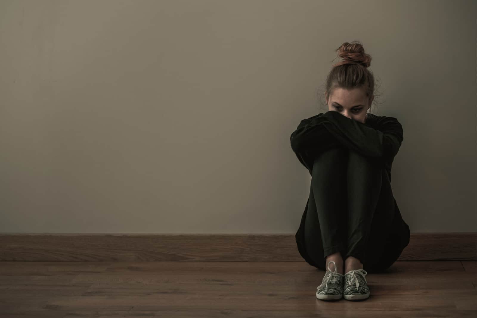 sad woman sitting on floor near wall