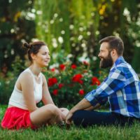 uomo e donna che sorridono seduti sull'erba