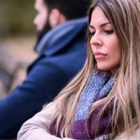 sad woman with scarf sitting next to man outdoor