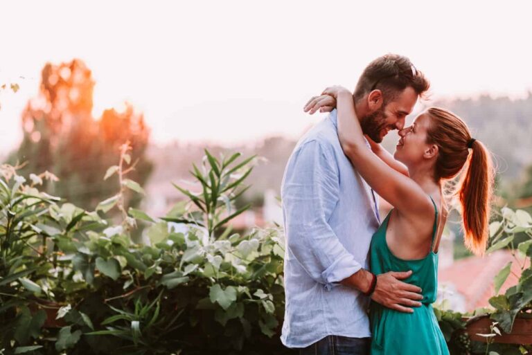man and woman hugging while standing near plants