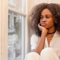 pensive woman with curly hair sitting near window