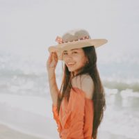 donna felice con cappello in piedi sulla spiaggia