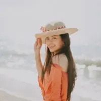 happy woman with hat standing on the beach