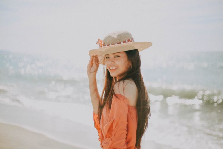 happy woman with hat standing on the beach