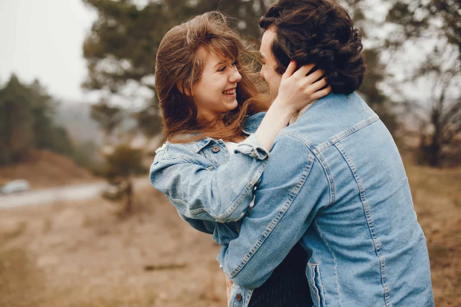 man and woman in denim jackets hugging outdoor