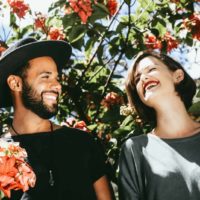 man and woman laughing while standing near flowers