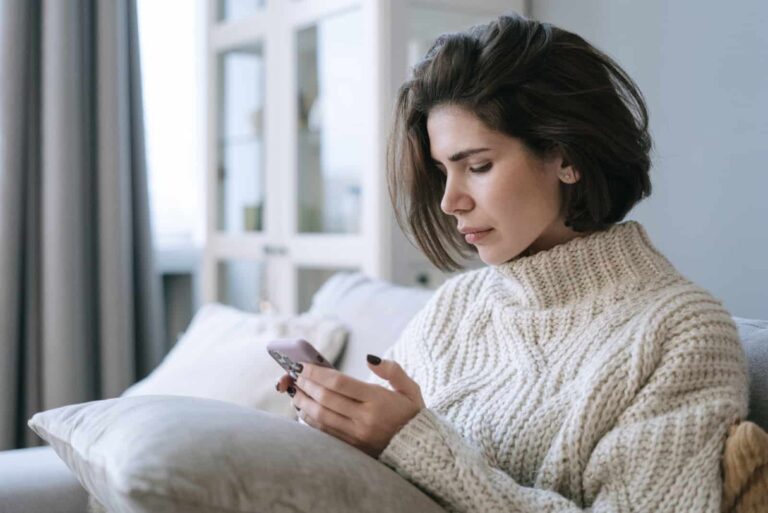 woman looking at smartphone sitting on sofa
