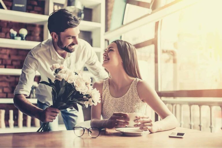 mujer sorprendida por las flores regaladas por su novio mientras esperaba dentro de una cafeteria