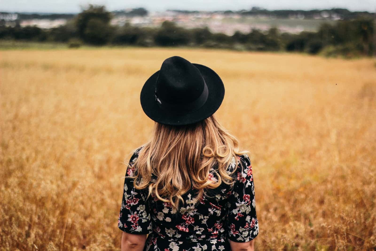 woman with black hat standing in the field