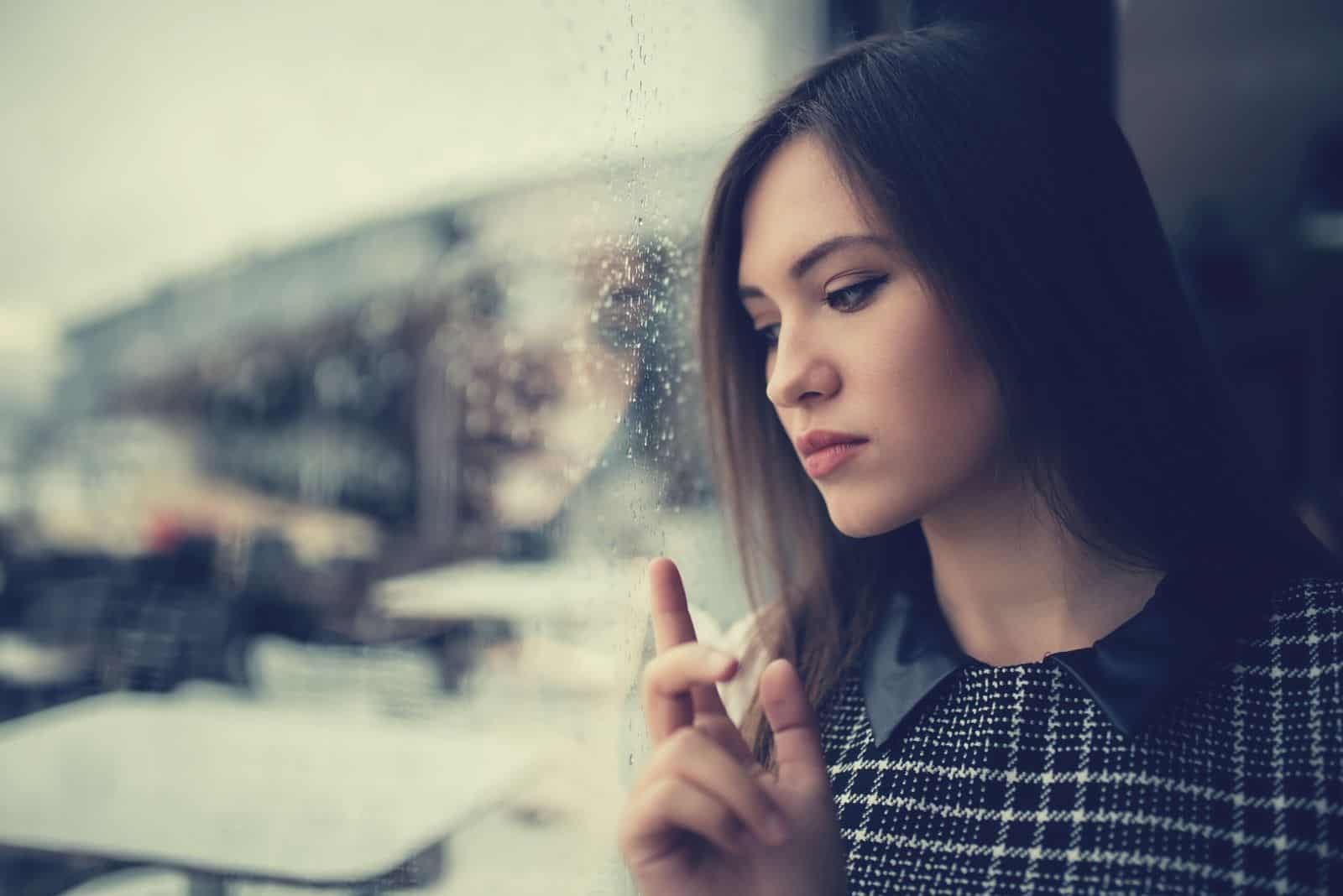 beautiful causcasian woman standing alone beside the glass wall 