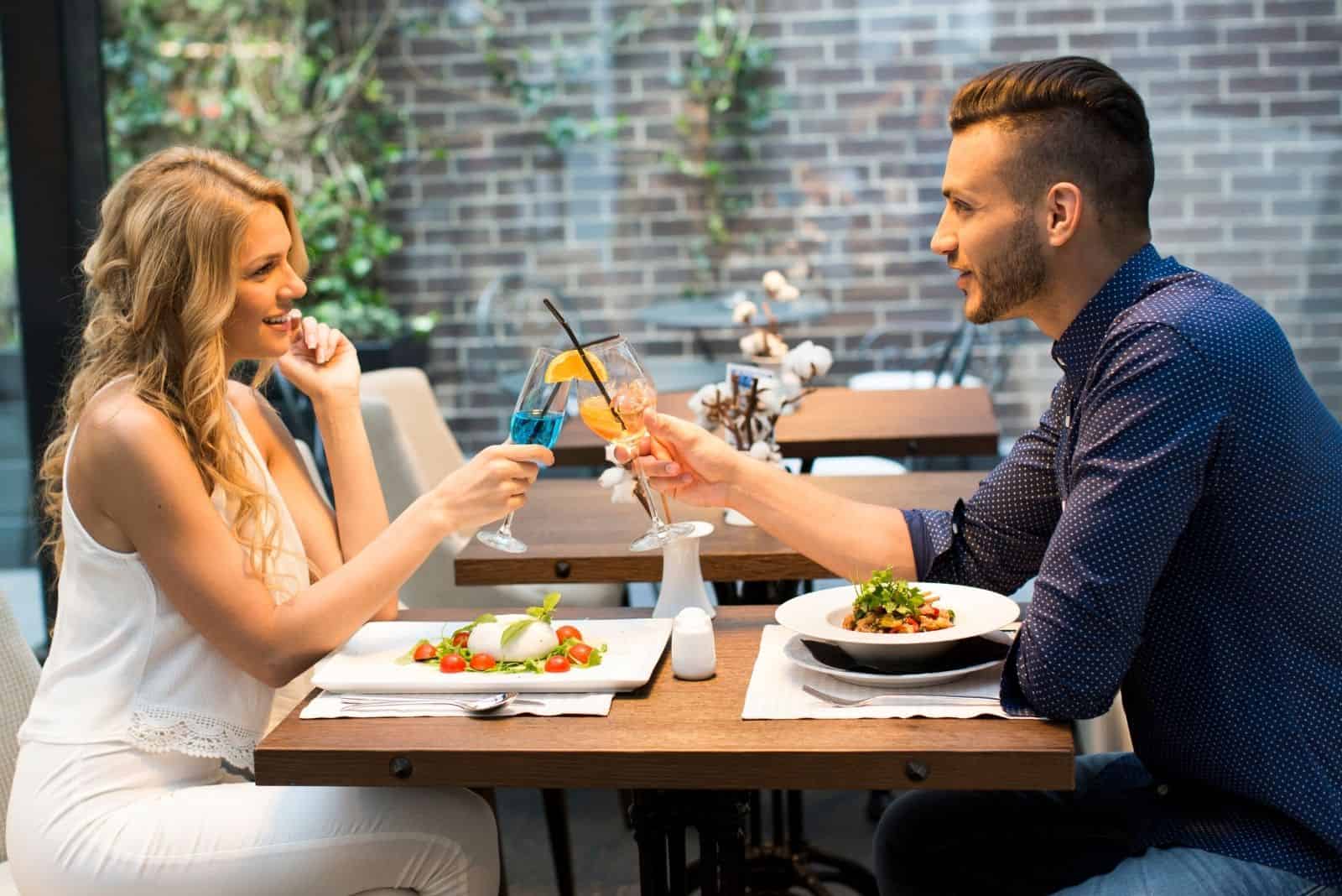 schönes Paar bei einem Date in einem Restaurant, das an seinem Weinglas klirrt 