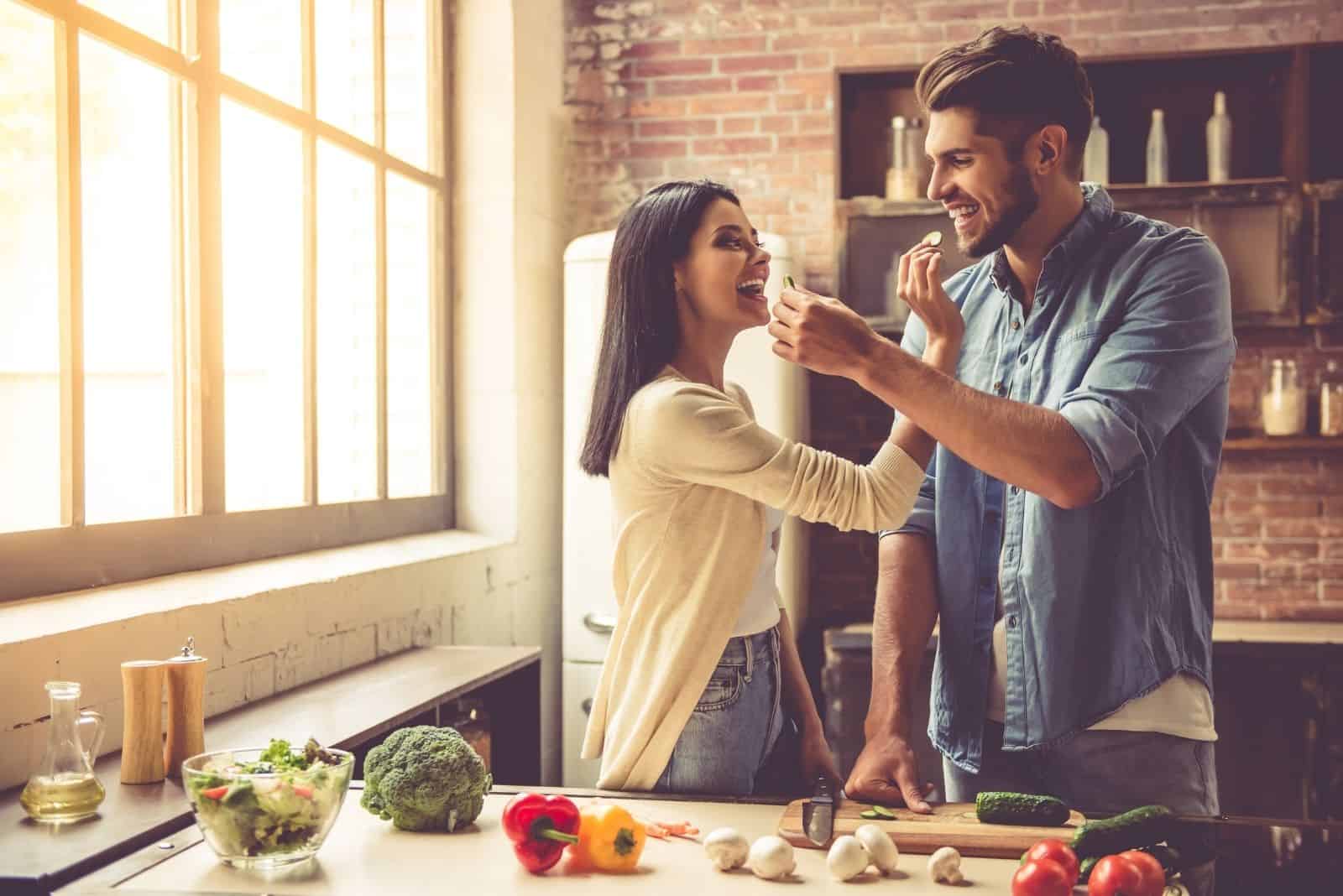 beautiful couple is feeding each other playfully in the kitchen