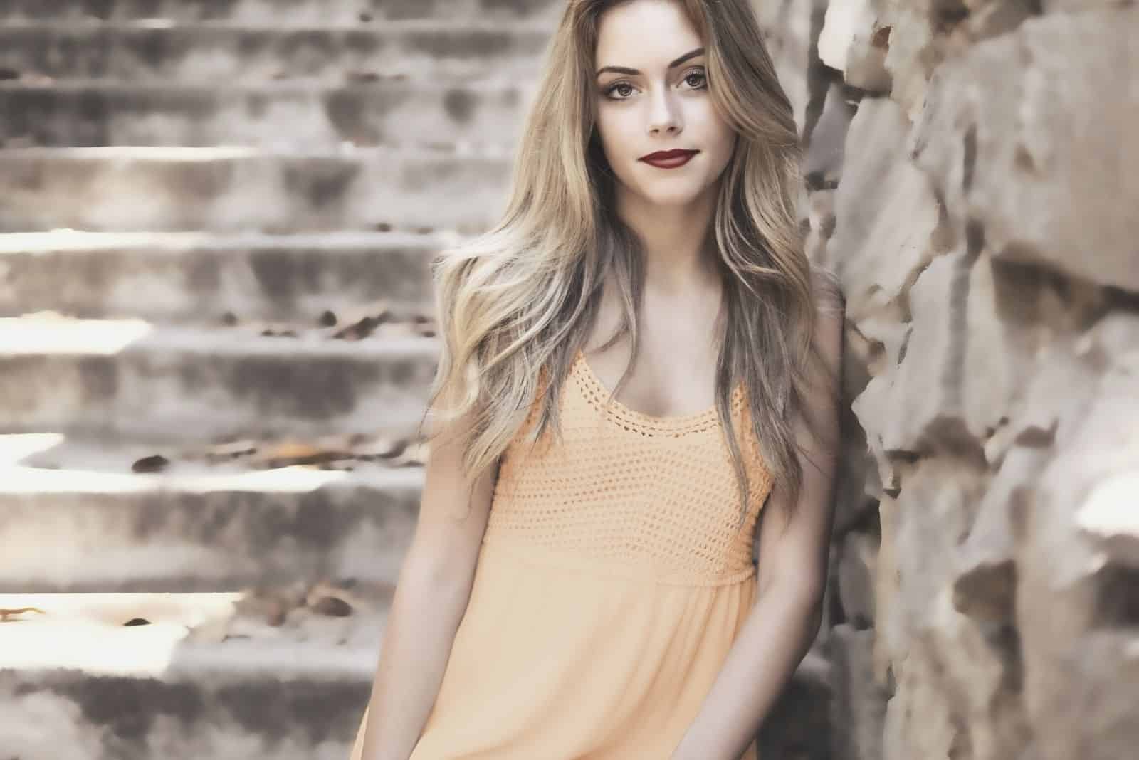 beautiful woman leaning on the rock wall by the stairs standing