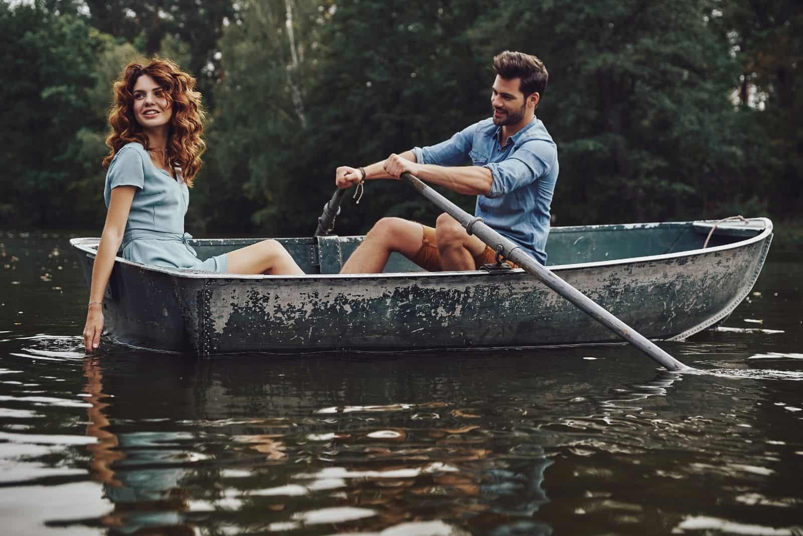 beautiful young couple enjoying riding a boat while rowing a boat